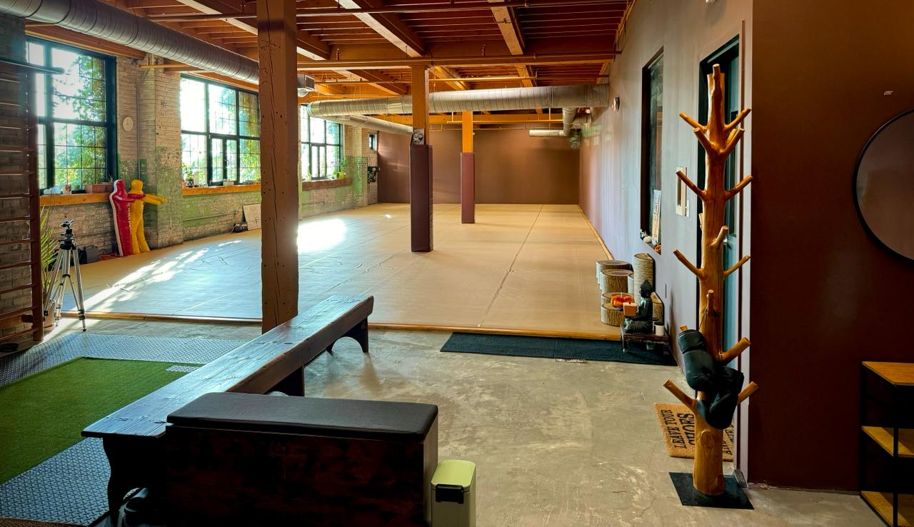 The Garden MMA dojo — spacious mat area with natural light, exposed wooden beams, and grappling equipment